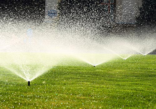 four lawn sprinklers shooting water